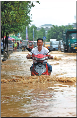 A man rides his scooter through a flooded street in Guilin, Guangxi Zhuang autonomous region, on Saturday. Provided To China Daily