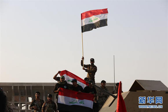 An Iraqi soldier holds a national flat to celebrate the liberation of Mosul. (Photo/Xinhua)