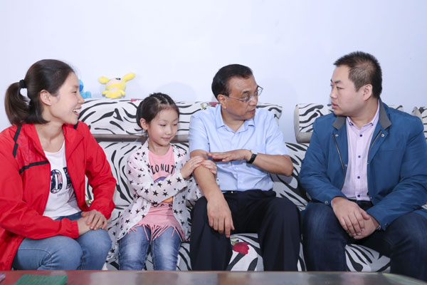 Premier Li Keqiang talks with Zhang Zhiqiang, a coal miner, at Zhang's home in Changzhi, Shanxi province, as Zhang's daughter holds his arm. Zhang was relocated to another mine after the place he used to work was closed amid the country's push to cut overcapacity. (LIU ZHEN/CHINA NEWS SERVICE)