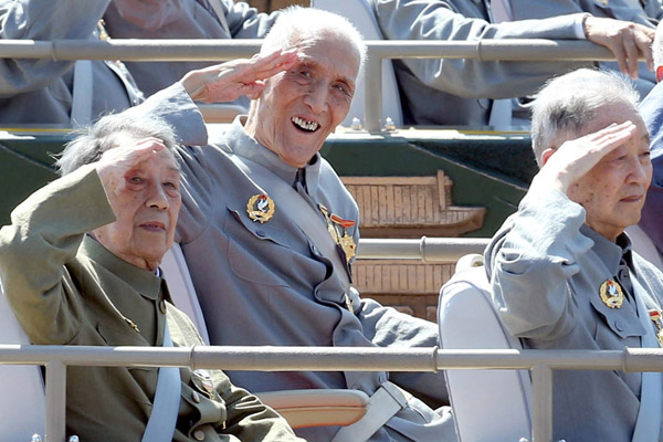 Retired Major General Zhang Yuhua (center) salutes with his right hand, which was wounded in war, while celebrating the 70th anniversary of the victory in World War II in 2015. FAN JUN/XINHUA