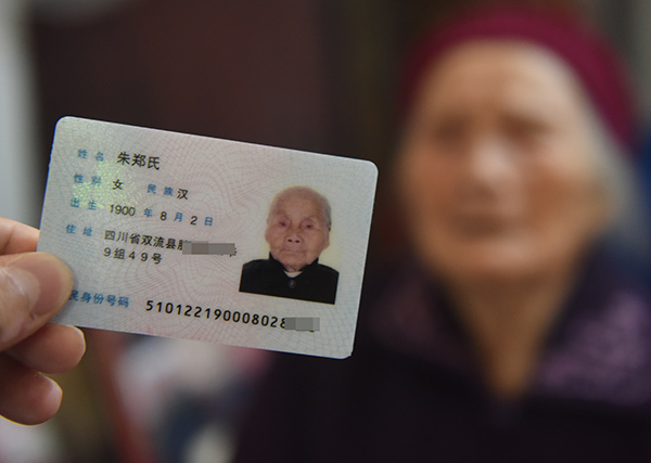 Zhu Zhengshi poses with her ID card in her courtyard in Chengdu, Sichuan province, on Monday. (Photo by Liu Chenping/China Daily)