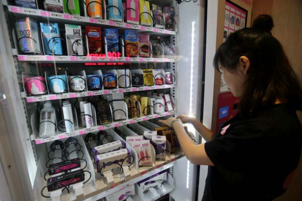 A member of staff at Beijing Lulu fills a vending machine with the company's products.(Photo by Wang Zhuangfei/China Daily)