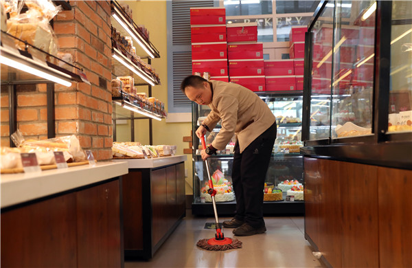 Liu Shunli, 24, who has Down syndrome, mops the floor at a branch of the Auspicious Phoenix Bakery in Beijing.(Photo by Zou Hong/China Daily)