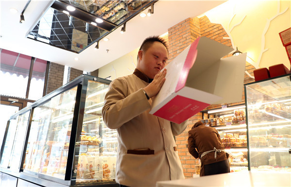 Liu Shunli, makes a cake box at a branch of the Auspicious Phoenix Bakery in Beijing.(Photo by Zou Hong/China Daily)