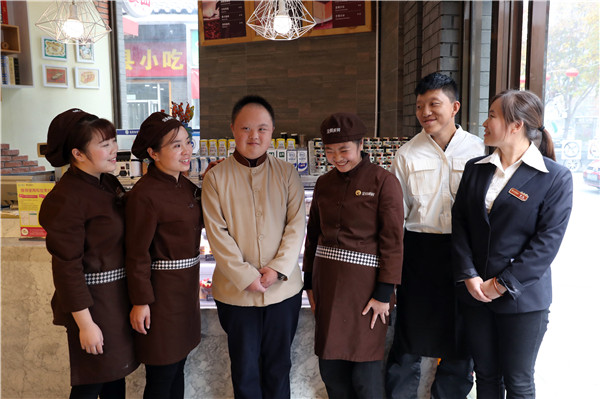 Liu Shunli and Yang Xiao pose for a group photo with other store assistants at the bakery in Beijing. (Photo by Zou Hong/China Daily)