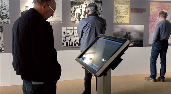 Visitors look at historical photographs at the exhibition Forgotten Camp. (Photo by Lia Zhu/China Daily)