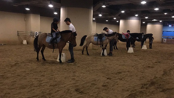 Coaches adjust the stirrups so that the children can ride comfortably. (Photo provided to chinadaily.com.cn)