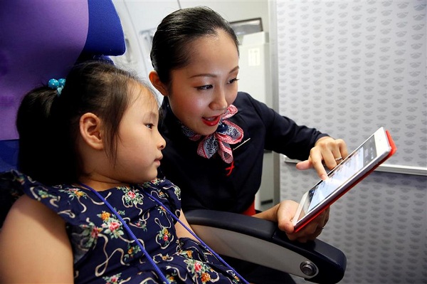 A flight attendant with China Eastern Airlines displays several services to a child passenger on an iPad on a flight yesterday. (Ti Gong)