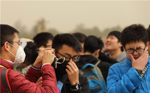 Tourists don masks at Tiananmen Square on a dusty day in Beijing on Wednesday. (WANG JING/CHINA DAILY)