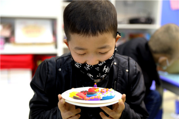 A boy shows off a piece of art he has made. (Photo provided to China Daily)