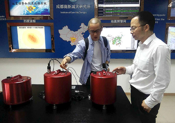 Wang Tun (right), head of the Chengdu-based Institute of Care-Life, demonstrates a seismic monitoring station.  (Photo: China Daily/Huang Zhiling)