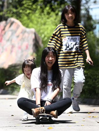 Two girls orphaned in the 2008 quake play with the orphanage manager's young daughter on Sunday. (ZOU HONG/CHINA DAILY)