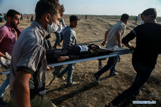Palestinians carry an injured man during clashes with Israeli troops near the Gaza-Israel border, east of Gaza City, on May 15, 2018. (Xinhua)
