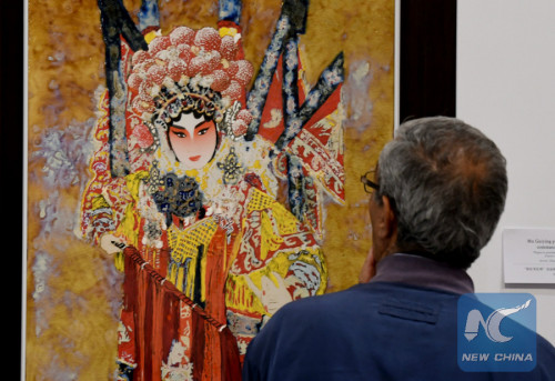 A visitor watches a porcelain artwork at Chinese Porcelain Art Exhibition in Tunis on May 17, 2018. (Xinhua)