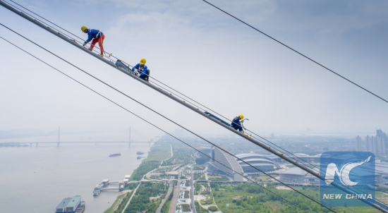 Workers install wire netting upon catwalk for the construction of a bridge across the Yangtze River in Wuhan, capital of central China's Hubei Province, May 8, 2018. (Xinhua/Ke Hao)