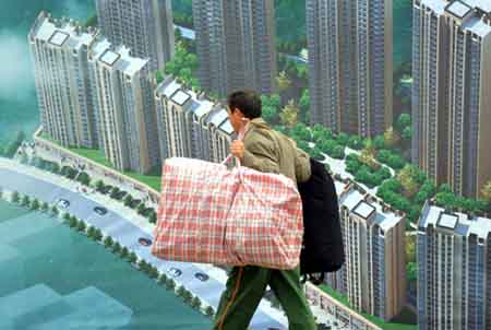 A migrant worker passes a poster for housing developments in Shaoyang, Hunan Province. [China Daily]