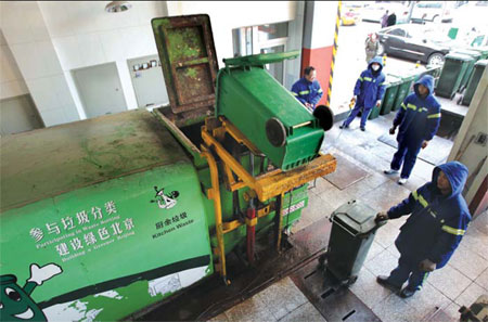 Sanitary workers put kitchen waste into a special garbage tank in a residential community in Beijing. Residents are encouraged to sort out their rubbish for recycling. [Photo / China Daily]