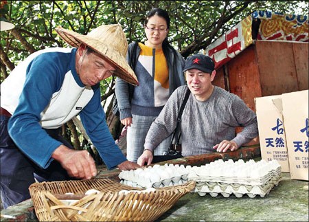 Two tourists buy sea duck eggs on Monday from Lin Dingxiu, a 60-year-old farmer who has been breeding sea ducks for years in the mangrove along the seafront of Dongxing, South China's Guangxi Zhuang autonomous region. [Photo / China Daily] 