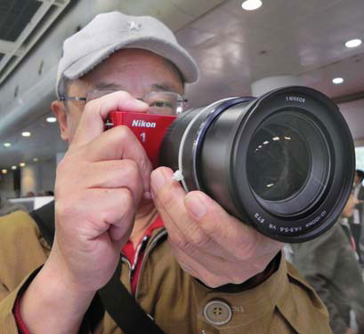 An enthusiast tests a mini digital single-lens reflex camera at a photographic equipment exhibition in Hangzhou, Zhejiang province. Mini SLR cameras have become a new and more cost-efficient choice for customers in the domestic market.[Photo/China Daily]