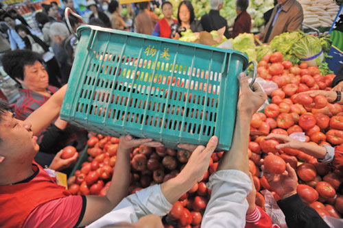 Two workers unloading tomatoes at a stall in a supermarket in Beijing. Most retailing giants in China have implemented direct purchase plans either by working with farmers' cooperatives or setting up growing bases.[Photo/China Daily]