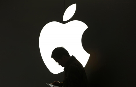 A man looks at his Apple iPad in front an Apple logo outside an Apple store in downtown Shanghai in this March 16, 2012 file photo. [Photo/Agencies]