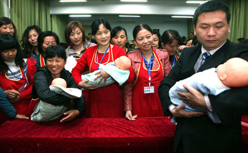 An official from a nursery service from Shenzhen shows potential babysitters how to take care of a baby in Xiangyang, Hubei Province. [Photo: Gong Bo / China Daily]