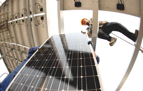 Workers from the State Grid Corporation of China install a solar photovoltaic power generation system on a roof of the first intelligent substation in Huaibei, Anhui province. [Photo / China Daily]