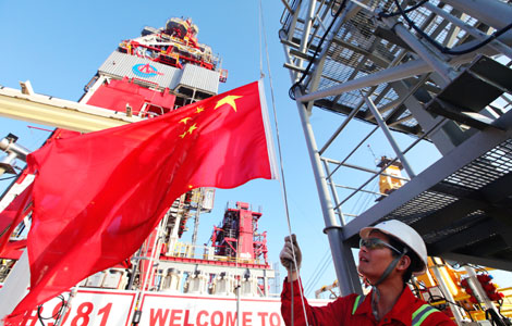 A worker raising a national flag at the Haiyangshiyou 981 oil rig. China, as the world's second largest oil consumer, is accelerating its pace of exploring for oil and gas in deepwater areas in the South China Sea. [Photo / China Daily] 