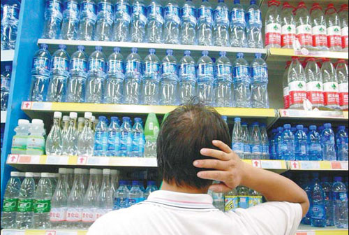 A customer stands in front of shelves filled with numerous brands of bottled water. China's high-end bottled water market was 3 billion yuan ($471 million) last year, and it's expected to grow to 10 billion yuan in 2015. Wu Huang / For China Daily