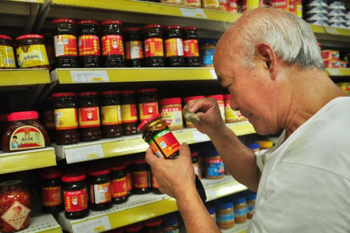 A man scrutinizes the production date of canned food at a supermarket in Ningbo of Zhejiang province on Sunday.HU XUEJUN / FOR CHINA DAILY