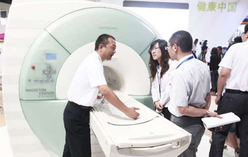 A salesman shows a computer tomography machine at the 20th China International Medical Equipment & Affiliated Facilities Exhibition and Scientific Conference. Many international medical-care companies, including drugmakers and medical-device producers, have begun conducting research and development in emerging markets such as China. [Photo/China Daily]