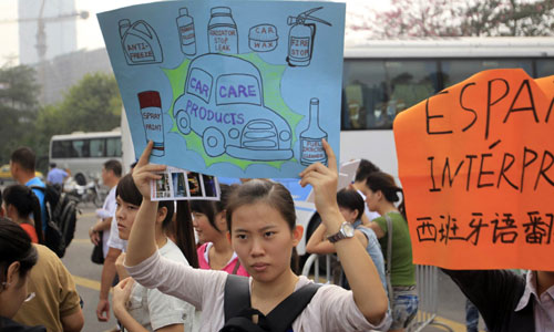 University students seeking jobs as interpreters wait outside the Guangzhou International Convention and Exhibition Center in the capital of Guangdong province, where the biannual Canton Fair is being held. Many said it is more difficult to find such a job because of dwindling number of foreign visitors. [Photo/China Daily]