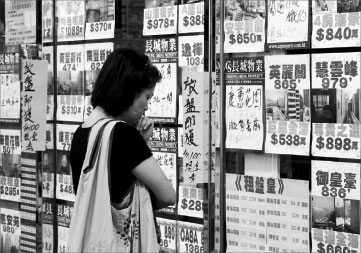 A woman looks at advertisements in the window of a local estate agency. Hong Kong people's confidence in their affordability to buy a home has fallen to a 4-year low, according to a CityU survey. Kevin Lee / Bloomberg 