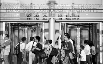 Pedestrians walk past Hong Kong Monetary Authority's office. Although the city's de facto central bank intervened in the foreign exchange market, a new wave of hot money is flooding into Hong Kong. Ted Aljibe / AFP Photo 