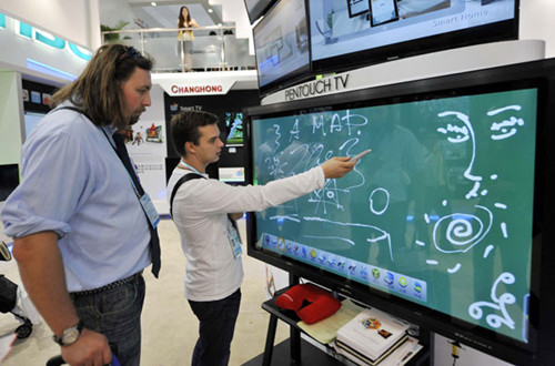 Two visitors sample an innovative product, a television that can interact with audiences, at a booth at the 112th China Import and Export Fair, also known as Canton Fair, in Guangzhou, capital of Guangdong province, on Oct 17. [Photo/Xinhua]