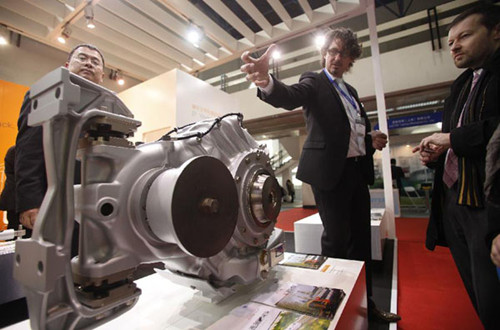 A staff member (C) of a German manufacturer introduces their high-speed wheel gear box for bullet trains at Modern Railway 2012 exhibition in Beijing, capital of China, Nov. 27, 2012. The four-day exhibition, China's largest trade show for the rail industry, kicked off on Tuesday in Beijing. (Xinhua/Wang Shen)