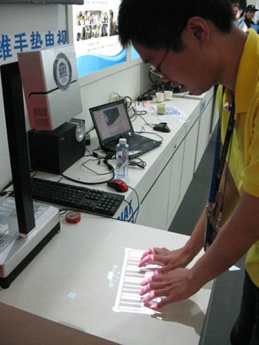 A staff member shows how to use an intelligent lamp developed by the Shenzhen Institutes of Advanced Technology at a fair in Shenzhen, Guangdong province, in November. The lamp can project onto a desk and turn it into a touch screen. [Photo by JIAN JIE / FOR CHINA DAILY]