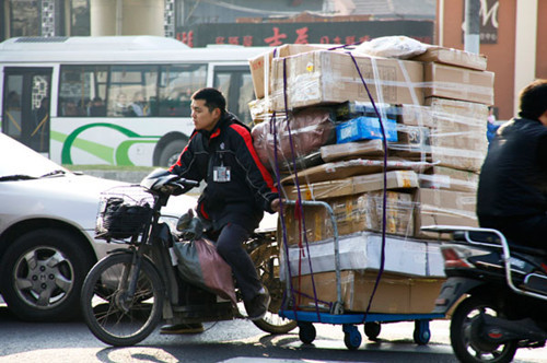 An S. F. Express employee riding a tricycle to deliver parcels to customers in Shanghai. The booming e-commerce market is fuelling demand for logistics services in China, a market that is characterized by a severe shortage of modern logistics stock. Gao Jianping / For China Daily 