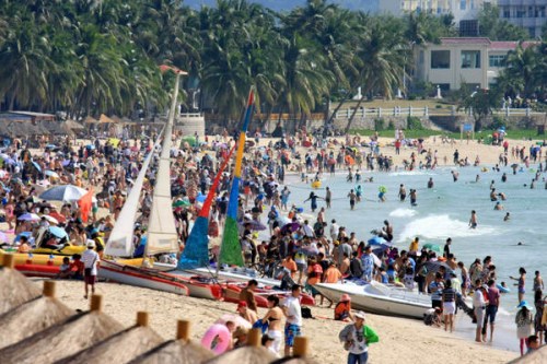 A beach is crowded with tourists spending their New Year holiday in the tropical city of Sanya, Hainan province, on Jan 2. [SUN QING / FOR CHINA DAILY]