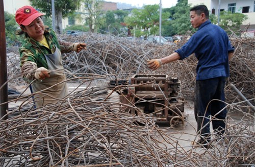 Workers at a construction site in Shangsi county in the Guangxi Zhuang autonomous region collect used steel rods, which will be straightened for reuse. [Photo/China Daily]