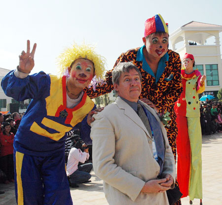 Clowns from the Shenzhen Happy Valley amusement park pose for photos with a foreign tourist at a carnival in Chengmai, Hainan province. YIN ENBIAO / FOR CHINA DAILY