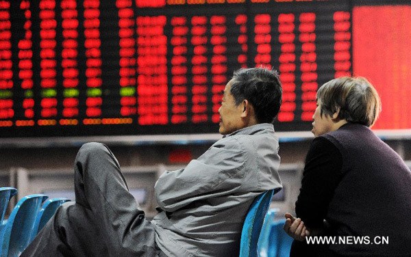 Investors look through stocks information in front of an electric board which shows stock price rise at a trading hall of a securities firm in Shanghai, east China, May 3, 2013. Chinese shares rallied on May 3 as the investors expect a newly-unveiled technical guideline will encourage greater foreign investment in China. The benchmark Shanghai Composite Index surged 1.44 percent, or 31.37 points, to end at 2,205.50. The Shenzhen Component Index gained 1.49 percent, or 129.48 points, to finish at 8,847.67. (Xinhua/Lai Xinlin)