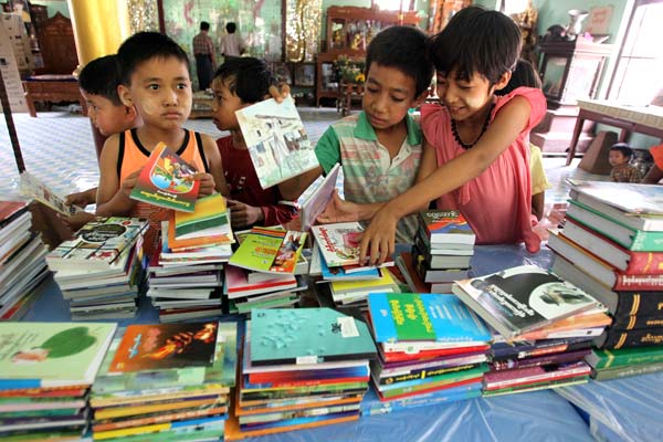 Pupils from villages near the Monywa Copper Mining Project accept books donated by Wanbao Mining. The Chinese company has promised to inject $1 million annually to build libraries, kindergartens and other infrastructure to benefit the local community. PHOTOS BY ZHANG WEI/CHINA DAILY