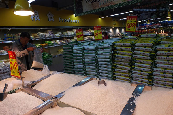 A shopper buys rice in a supermarket in Yichang, Hubei province. The bad weather that hit China's major rice-growing regions is likely to drive up imports in the world's biggest rice buyer.Liu Junfeng/For China Daily