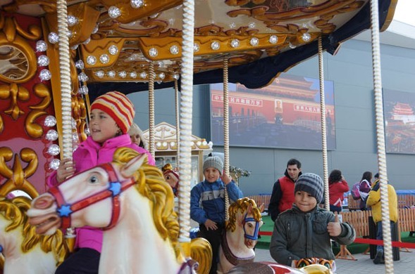 Children play on a merry-go-round in front of a newly-opened Chinese shopping mall in Bucharest, Romania, in this file photo. LIN HUIFEN / XINHUA  