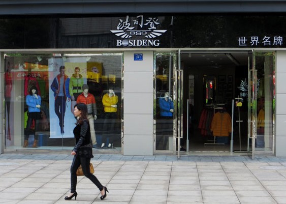 A woman walks past a Bosideng International Holdings Ltd store in Yichang, in central China's Hubei province. Liu Junfeng / for China Daily