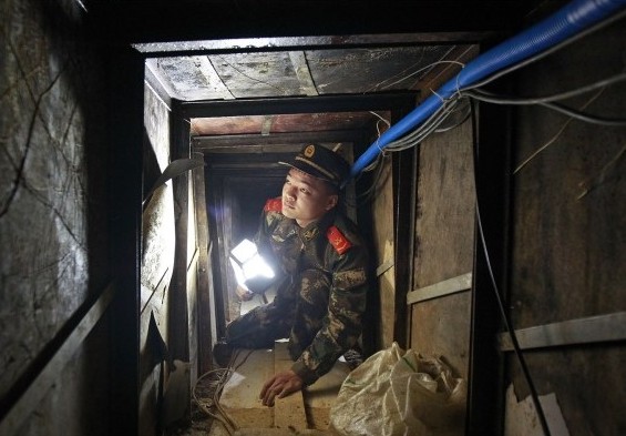 Border patrol officers inspect a hole on Tuesday. The hole was dug by smugglers in a garage to use as an underground passage linking Shenzhen, Guangdong province, and Hong Kong. Xue Yunhui / For China Daily