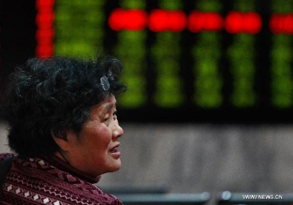 An investor looks through stock information in a trading hall of a securities firm in Shanghai, east China, March 10, 2014.  (Xinhua/Ding Ting)