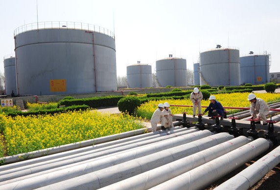 Workers inspect pipelines at a refined oil storage facility in Puyang, Henan province. Oil refining companies will have to eliminate units with annual capacity of less than 2 million metric tons as the country upgrades its production chain. Tong Jiang / For China Daily  