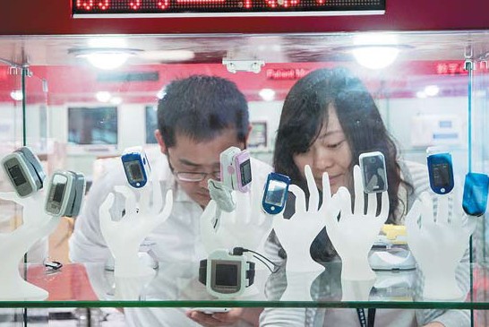 Two visitors check wearable electronic devices at an information technology expo in Shenzhen. Wearable devices, a new cool thing - just as smartphones were some years ago - are eagerly welcoming Chinese people to try them on. Provided to China Daily